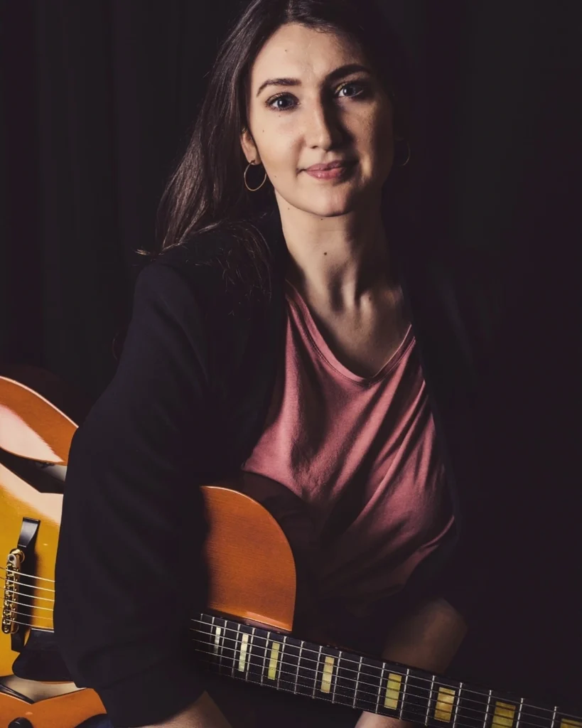Bailey smiling with guitar for Avid Guitar Studio
